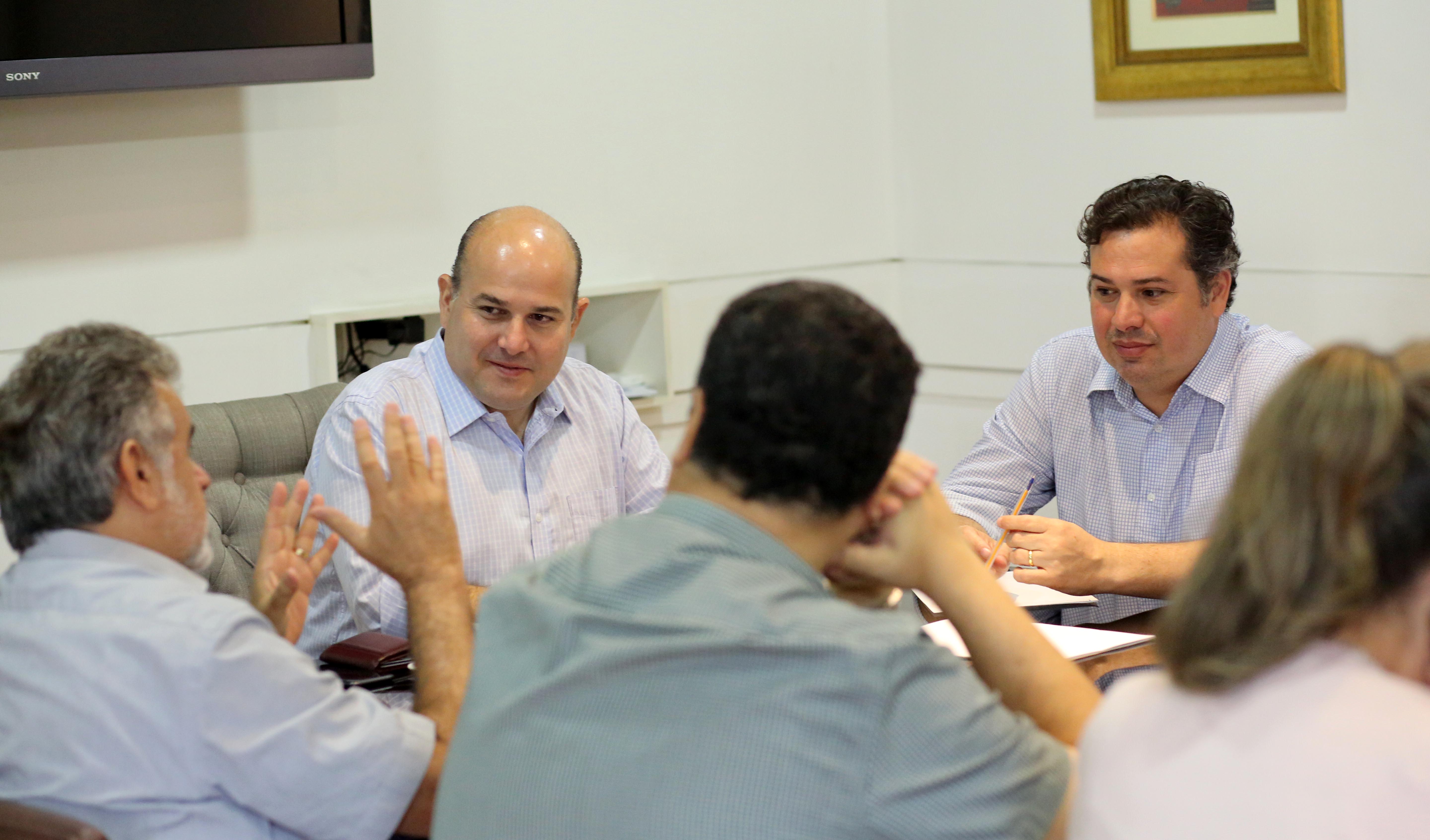 várias pessoas sentadas ao redor de uma mesa de reunião